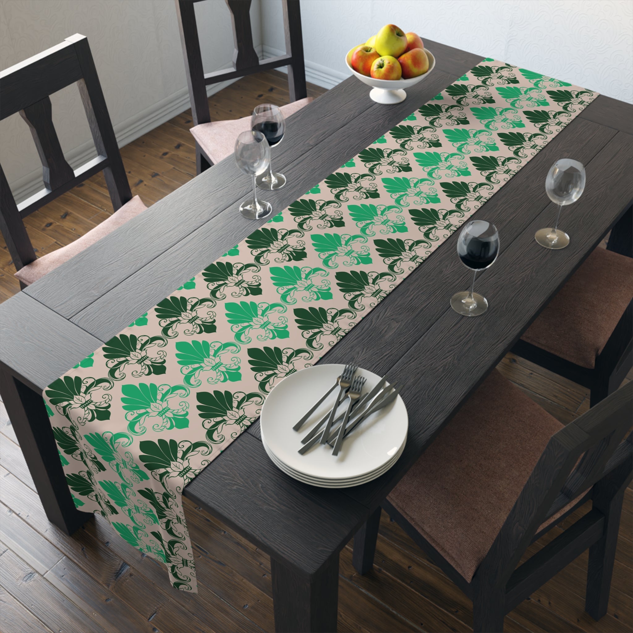 Dining table with a green leaf patterned table runner, plates, and glasses.