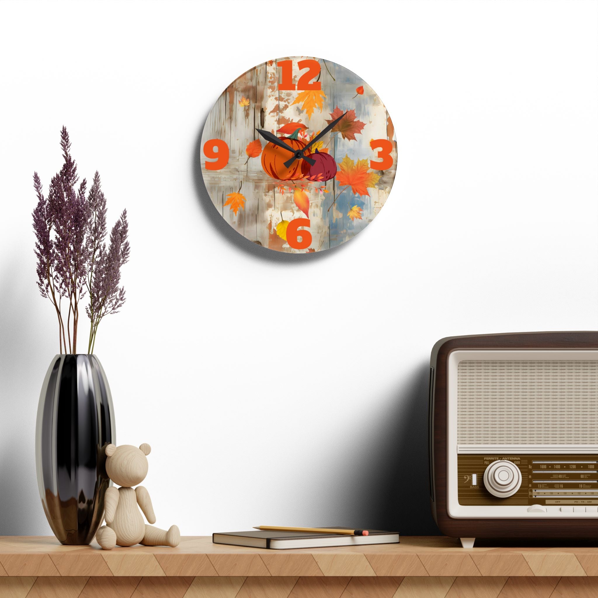 Decorative wall clock with autumn design on a shelf with a vase, teddy bear, and vintage radio.