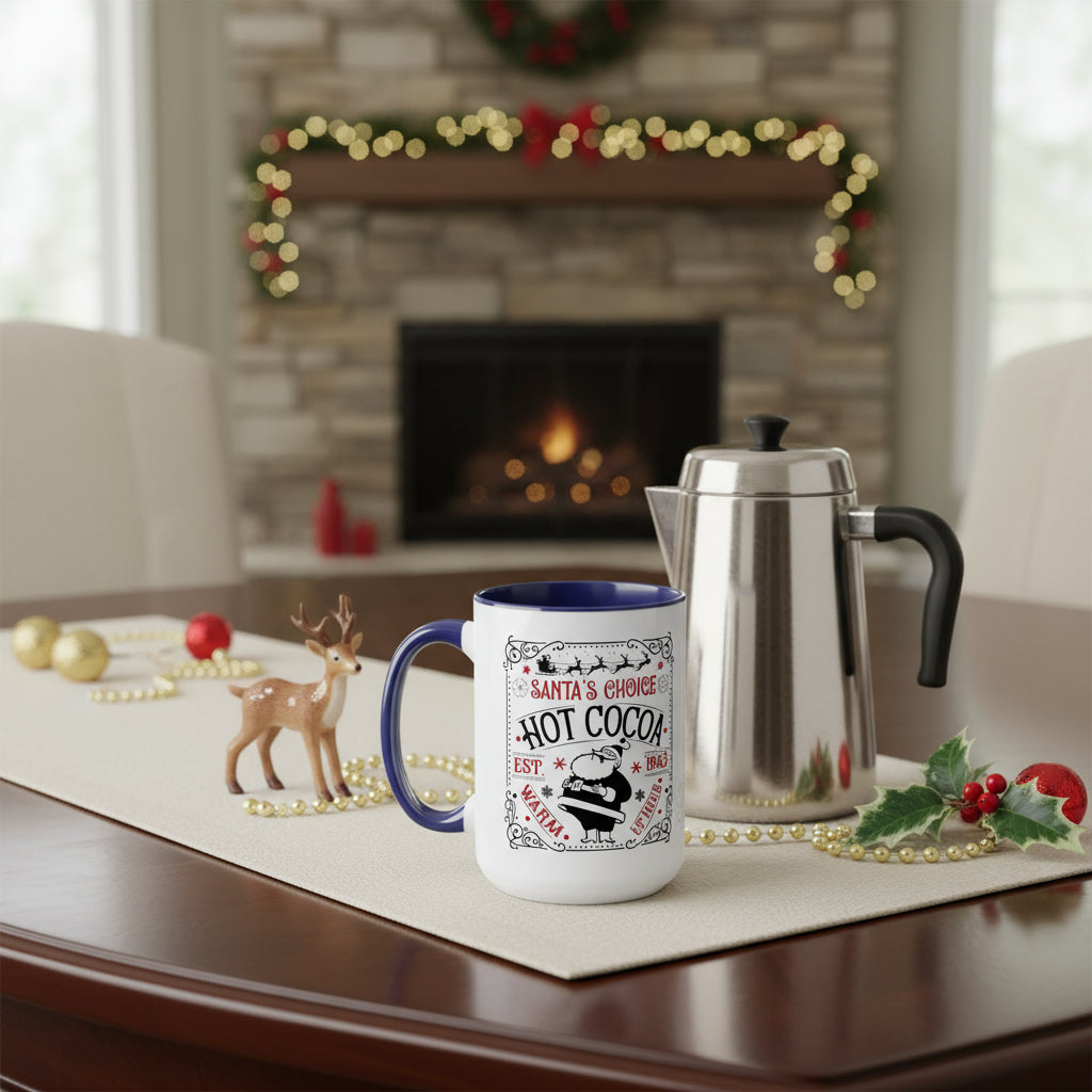 White mug with blue rim and festive design on a table in front of a fireplace, decorated for Christmas.