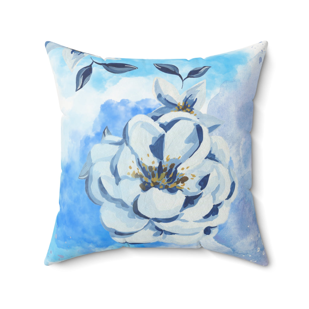 Decorative pillow with a white floral design on a blue watercolor background