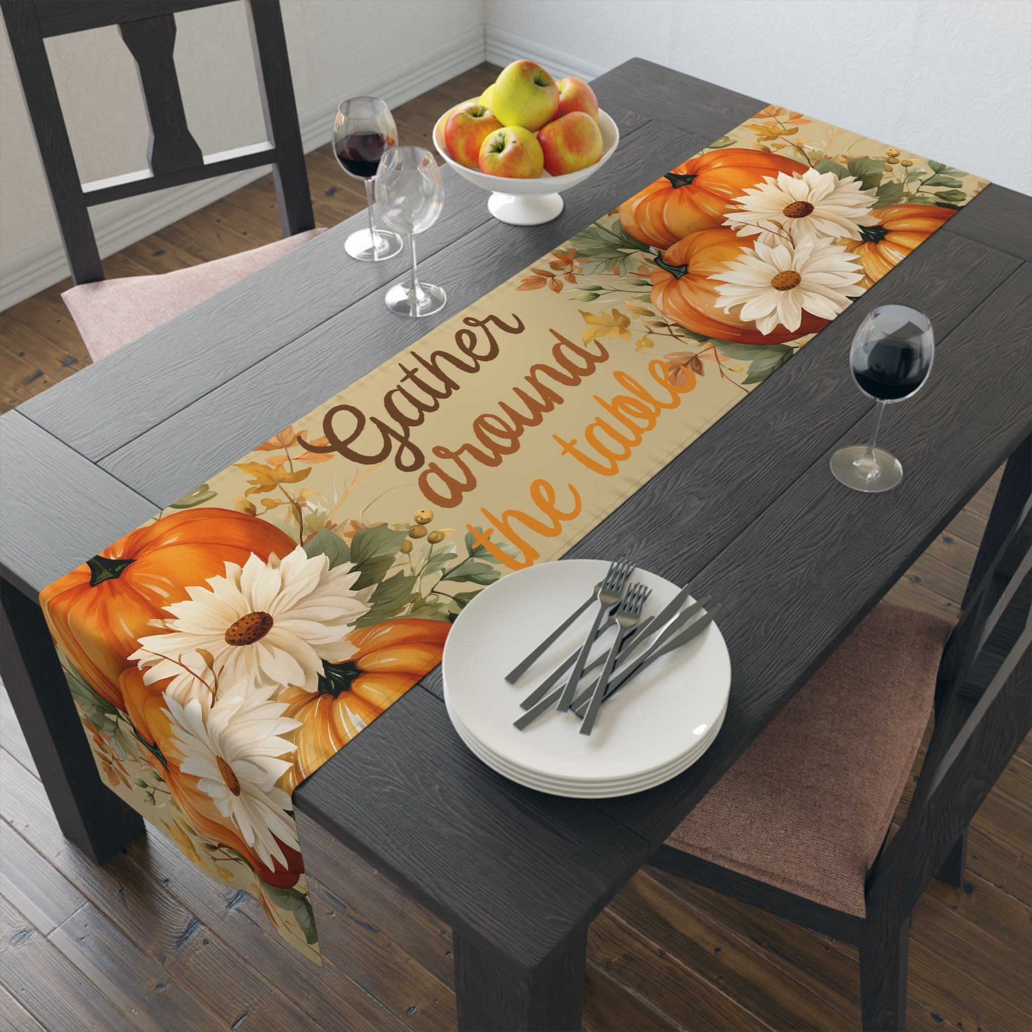 Table setting with a decorative table runner featuring pumpkins and flowers on a wooden table.