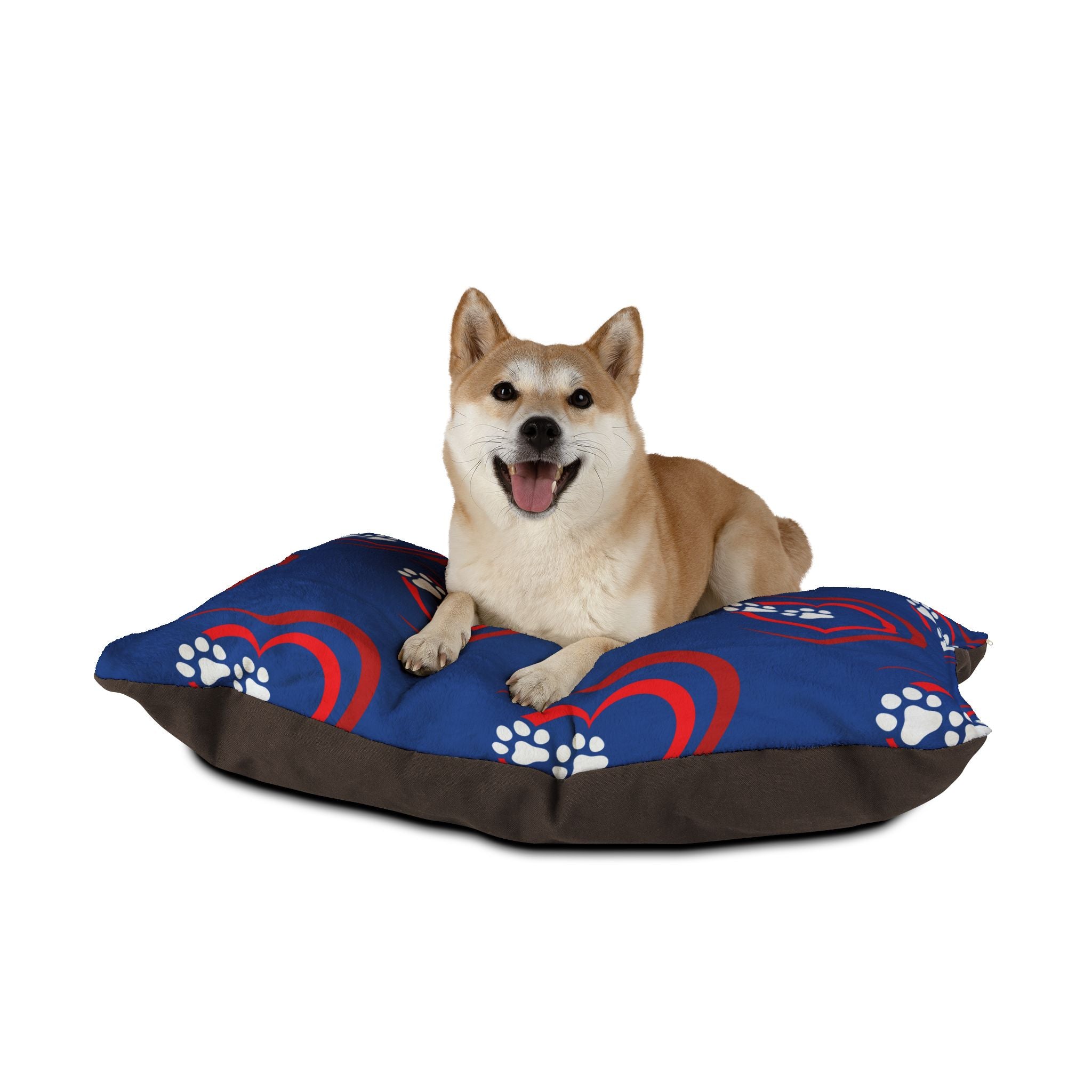 Dog sitting on a blue and brown pet bed with paw prints and heart designs.