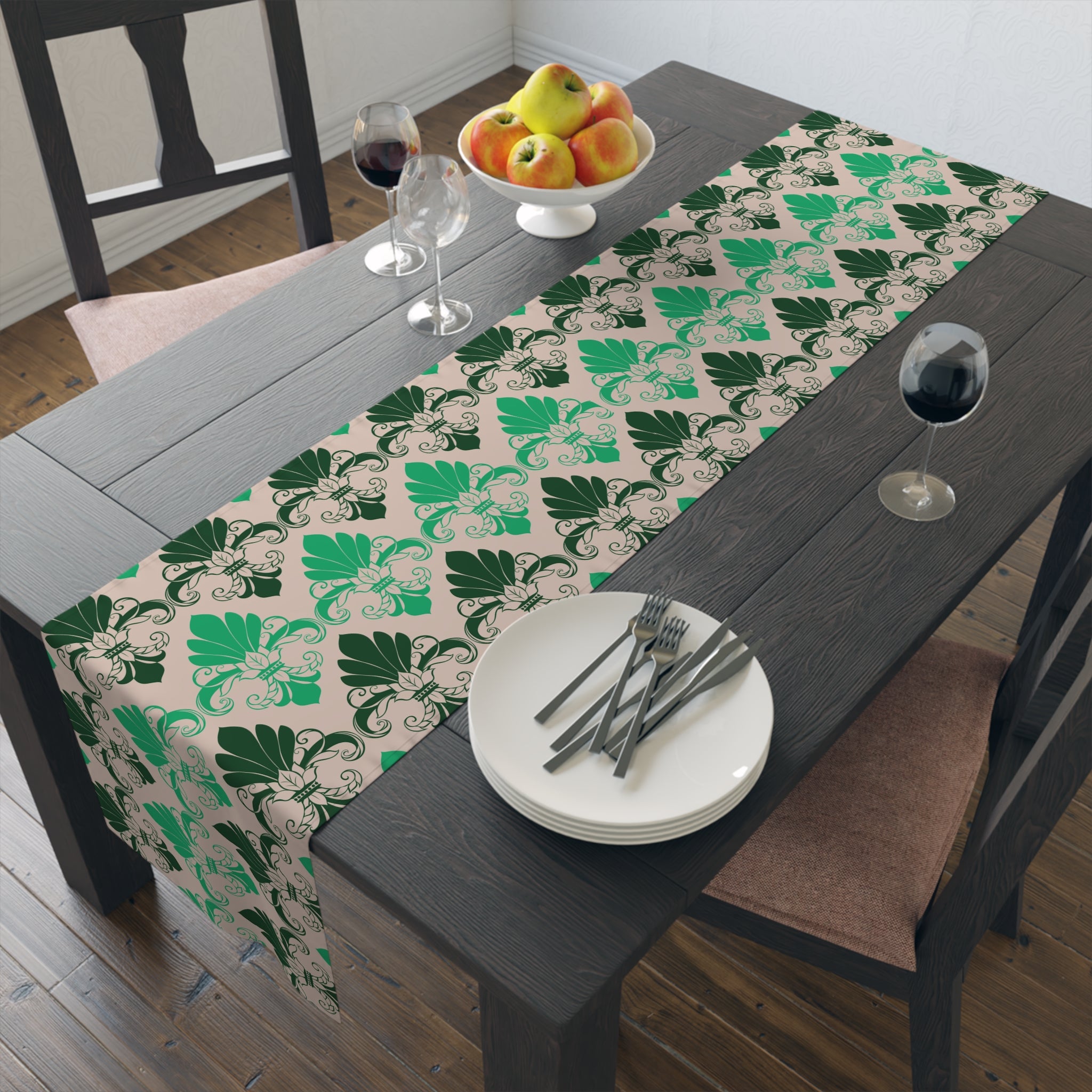 Dining table with a green and beige patterned table runner, plates, forks, and apples.