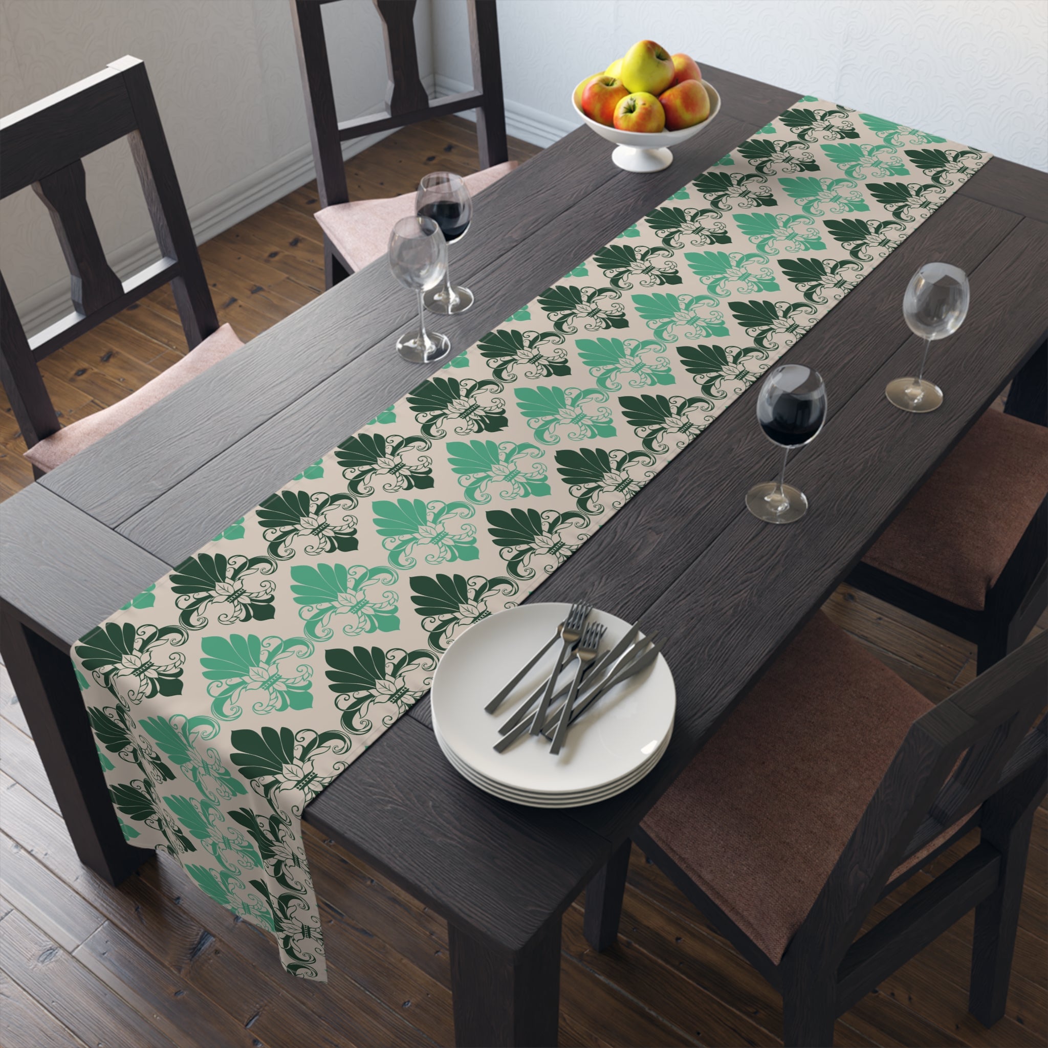 Dining table with a green leaf patterned table runner, plates, and glasses.