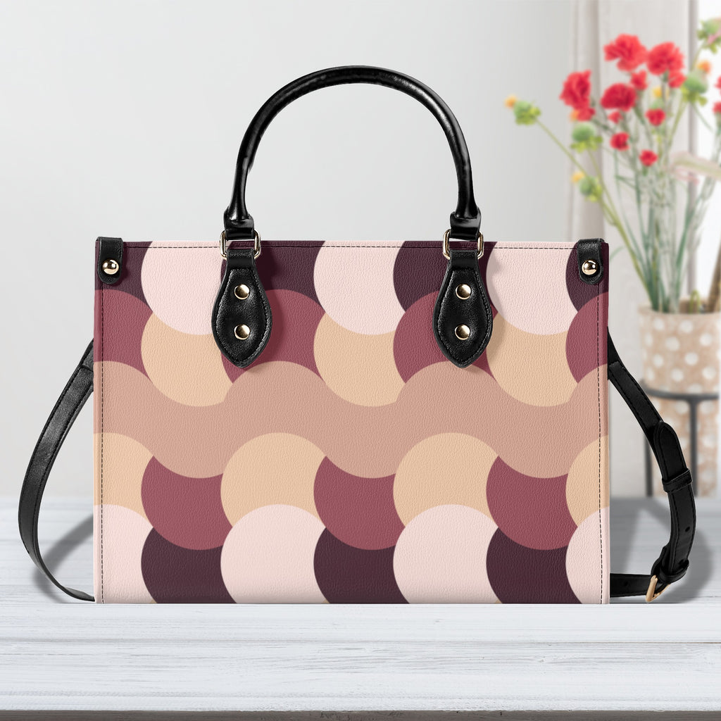 Patterned handbag with black handles and strap on a light background