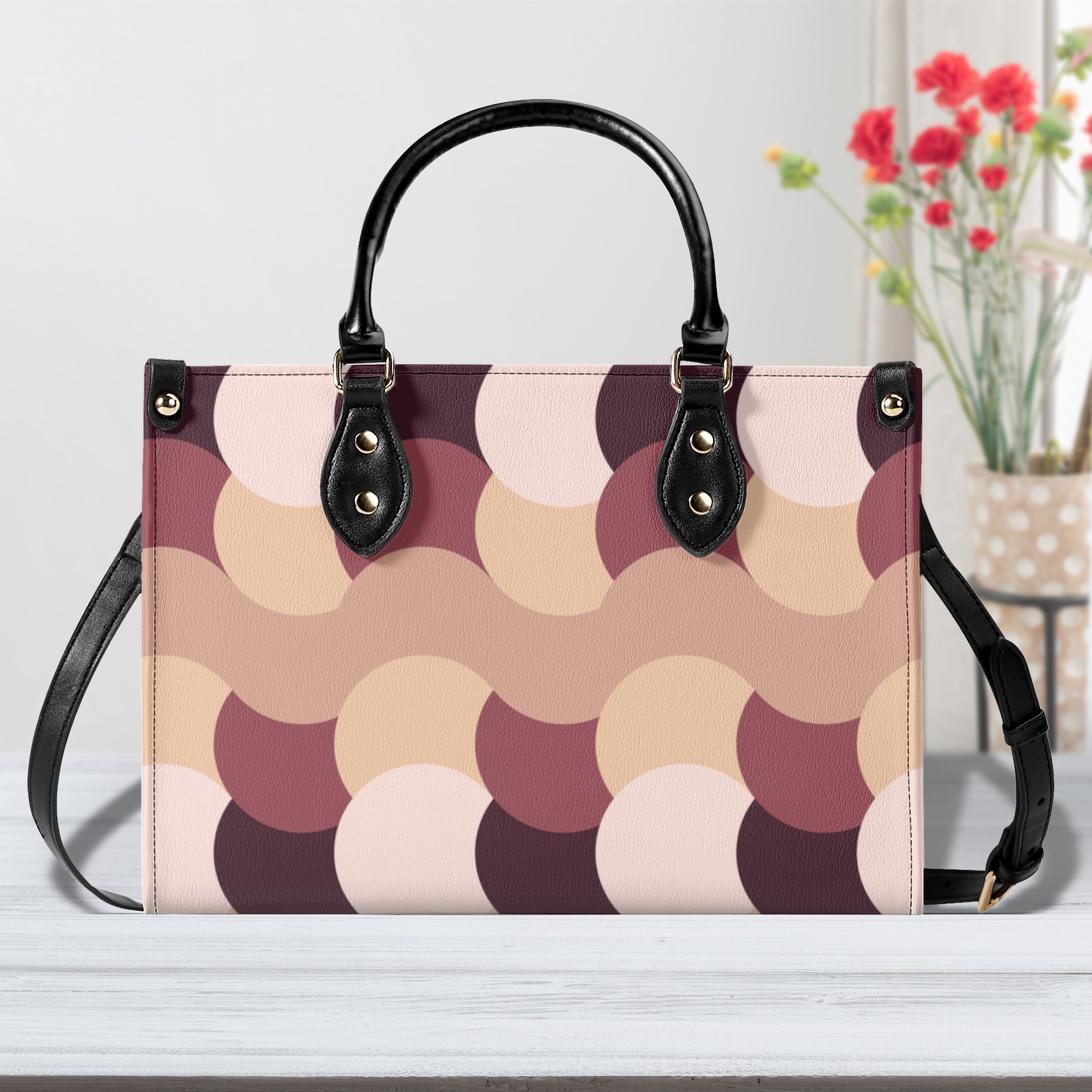 Patterned handbag with black handles and strap on a light background