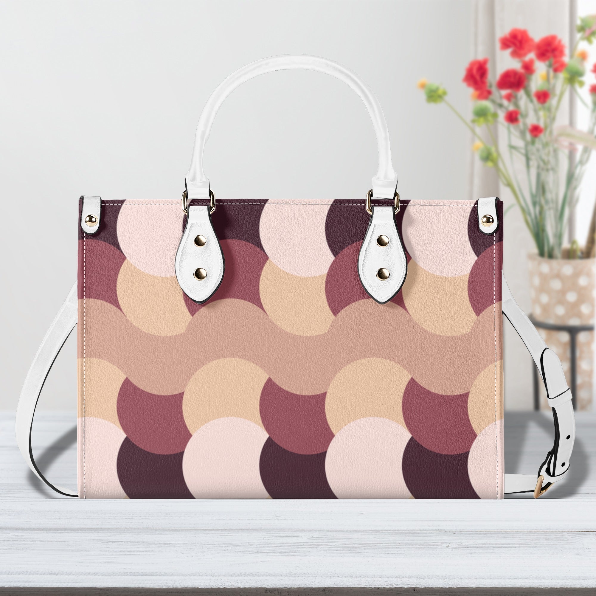 Patterned handbag with white handles and strap on a light surface.