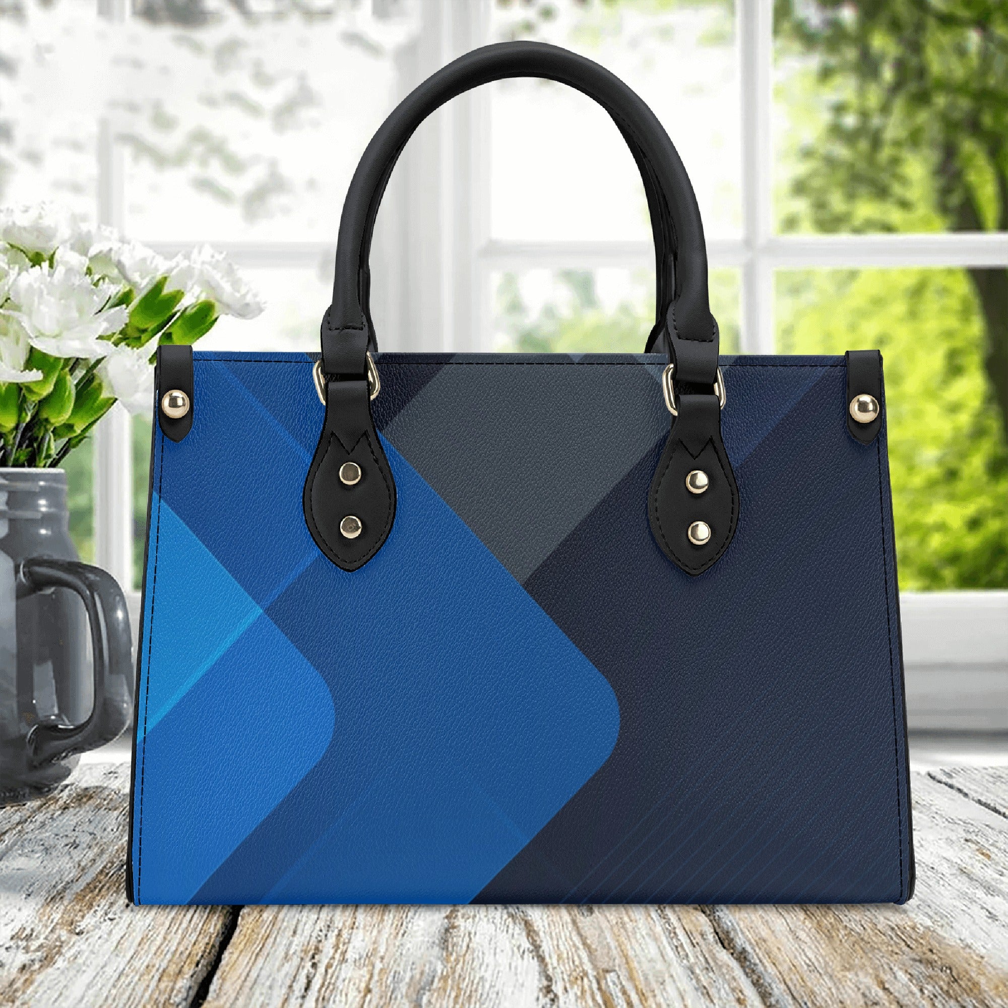 Blue and black handbag on a wooden surface with a blurred outdoor background