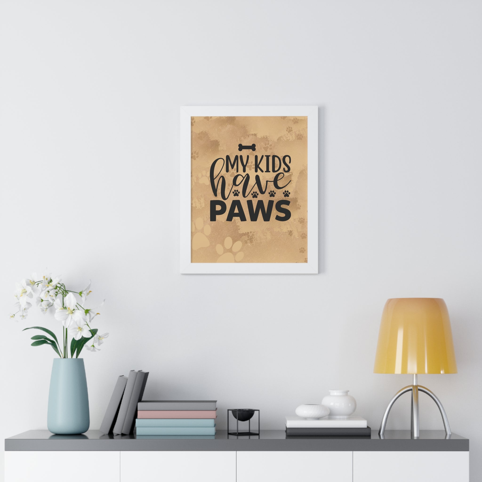 Framed print with 'My kids have paws' text on a wall above a desk with decor items.