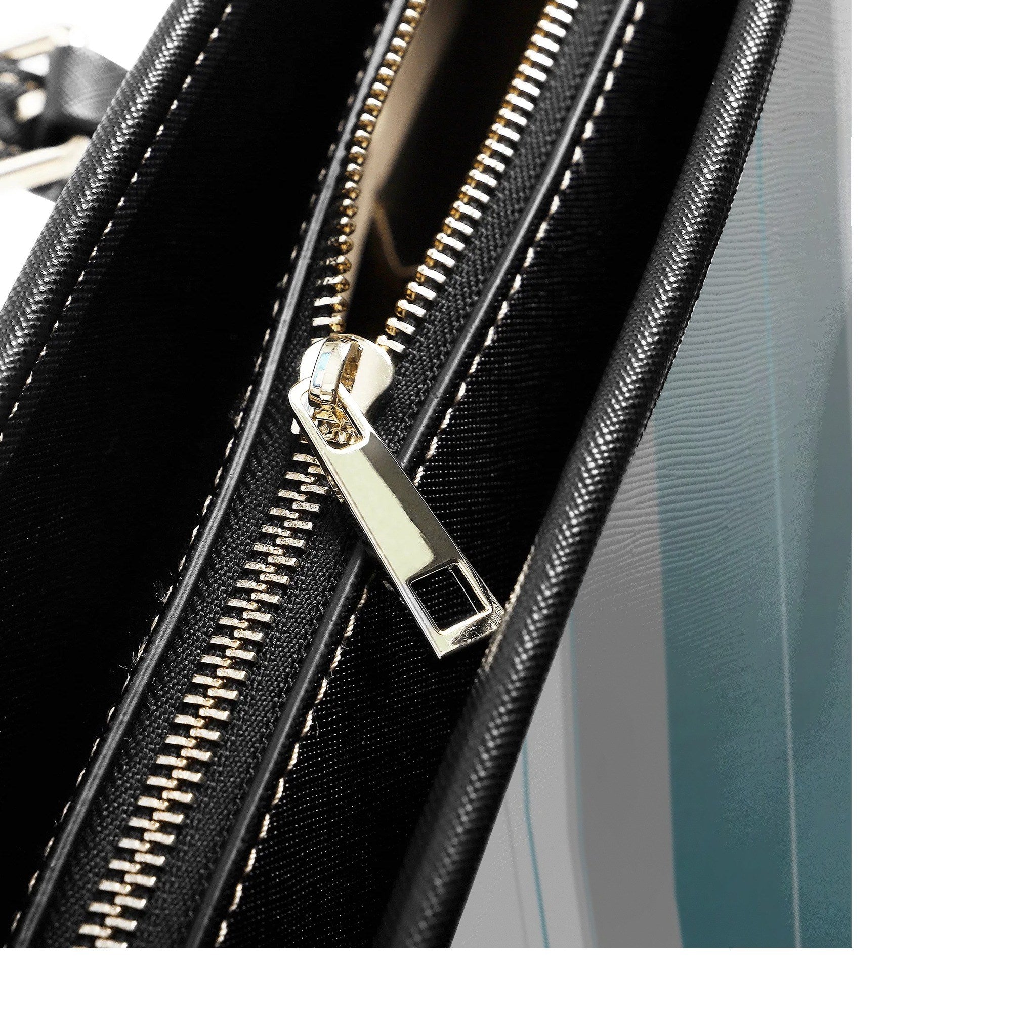 Close-up of a black suitcase with gold zipper pull