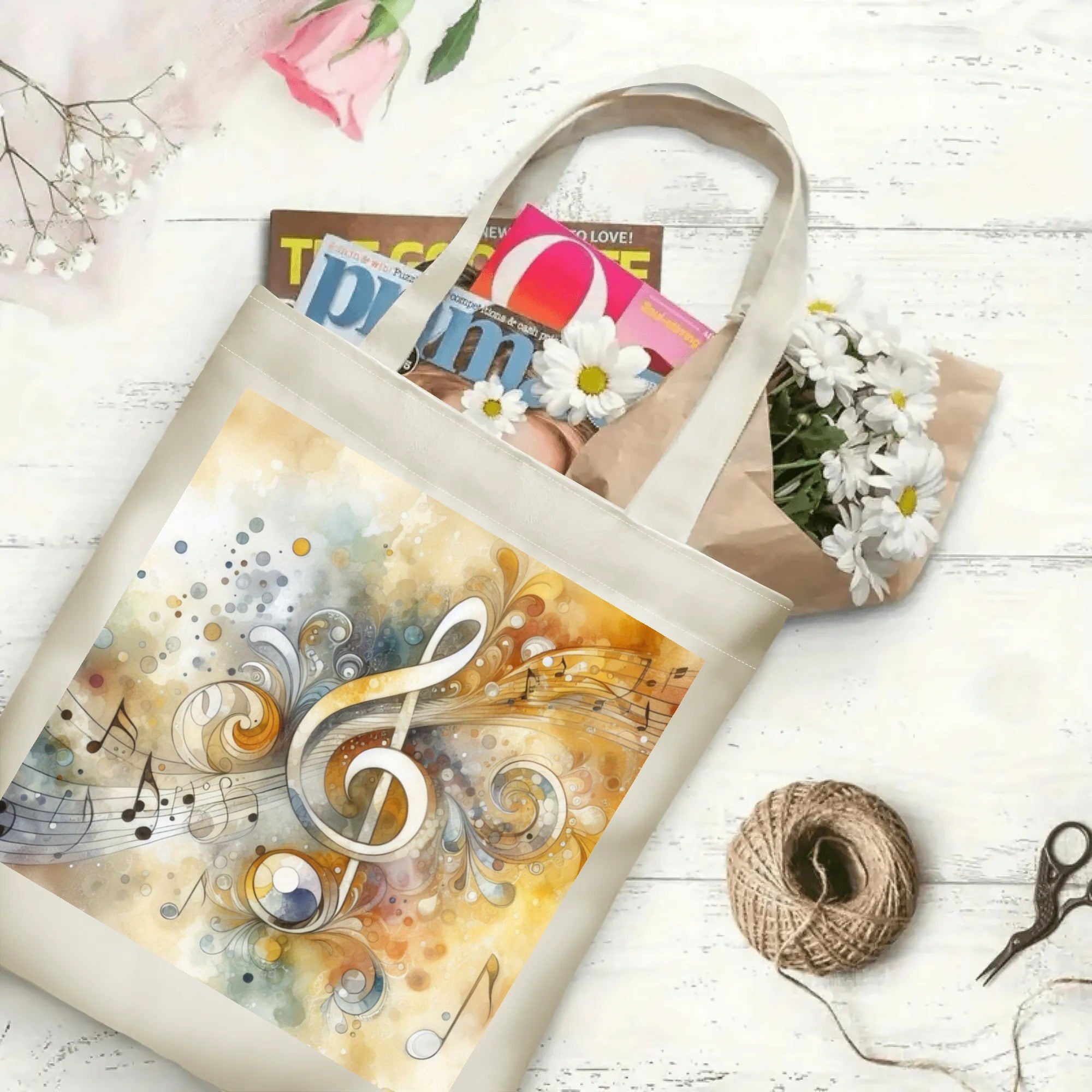 Tote bag with musical design on a white surface with flowers and magazines.