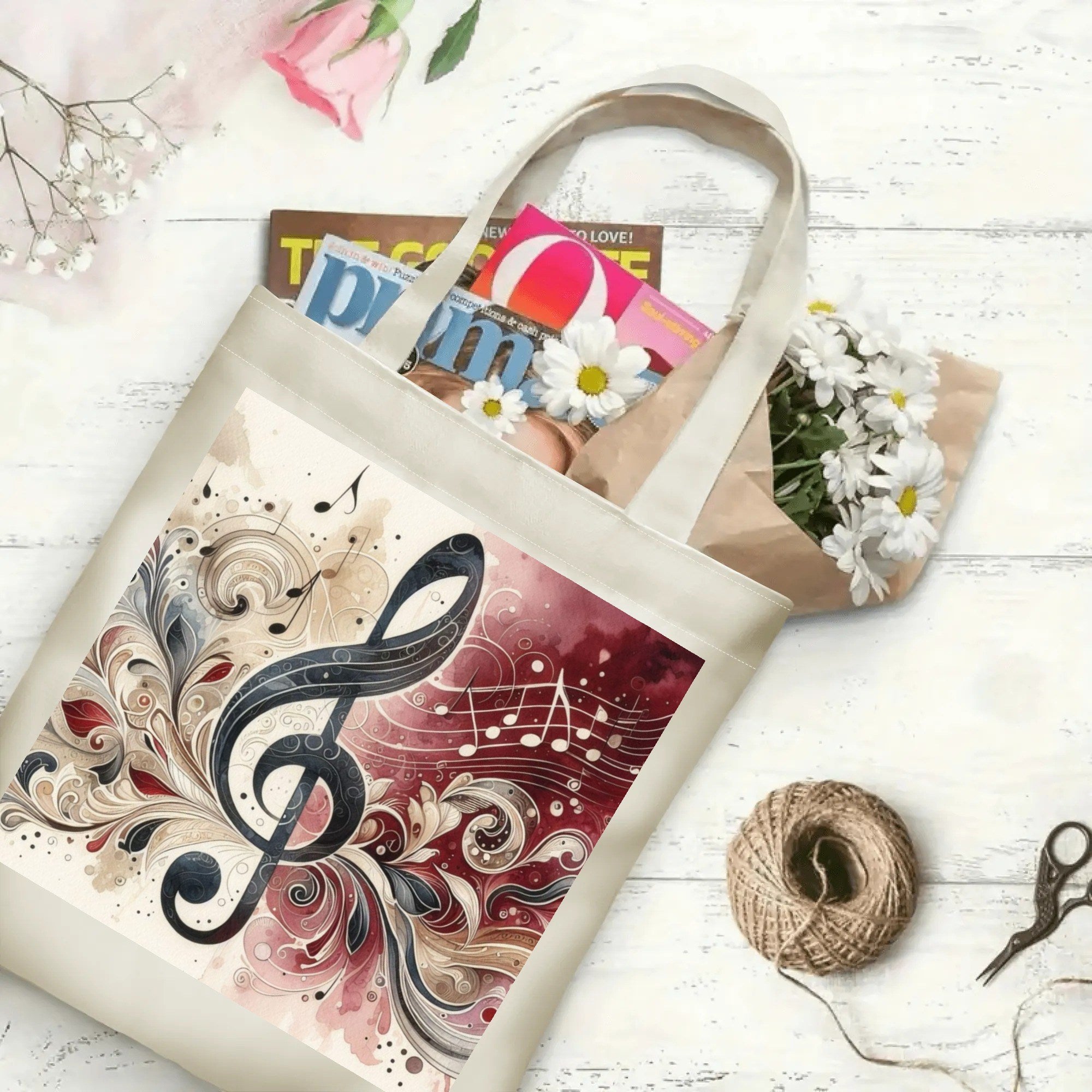 Tote bag with musical design on a white surface with flowers and magazines.