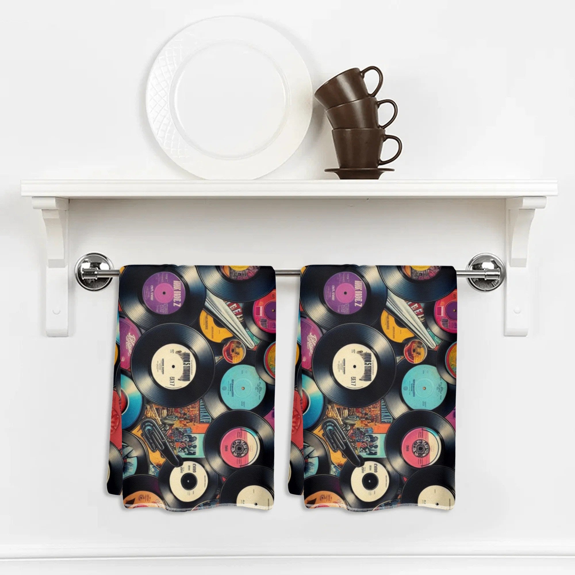 Kitchen towel with vinyl record design hanging on a white shelf.