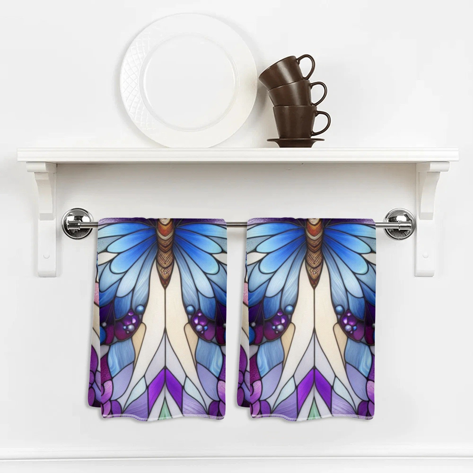 Butterfly-themed kitchen towels hanging on a white cabinet.