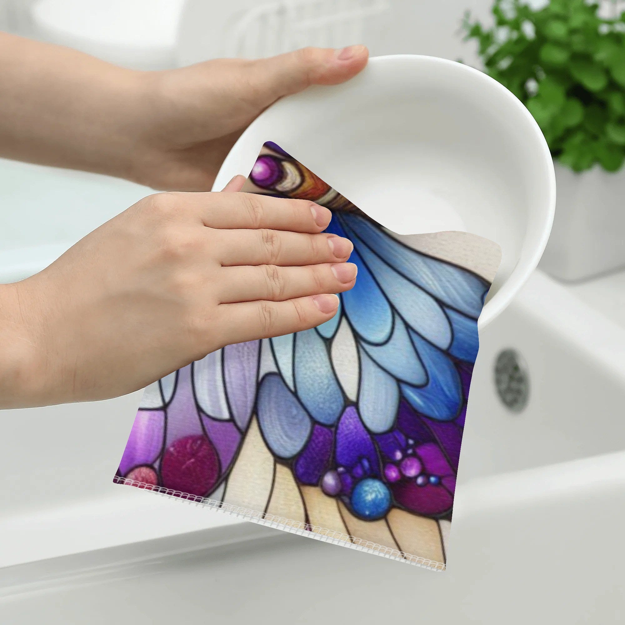 Hand cleaning a white bowl with a colorful butterfly design on a white surface.