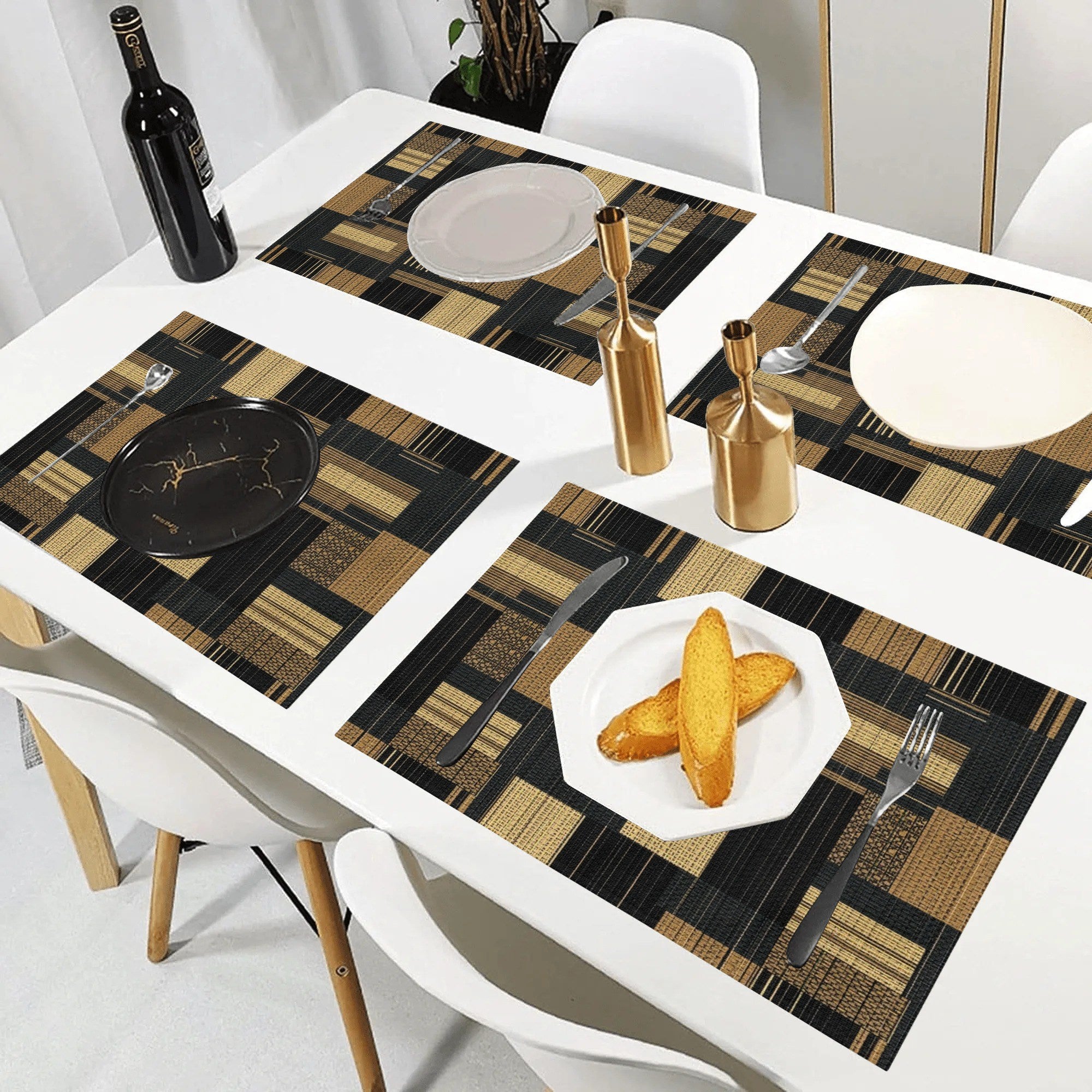 Dining table set with checkered placemats, plates, and cutlery on a white table.