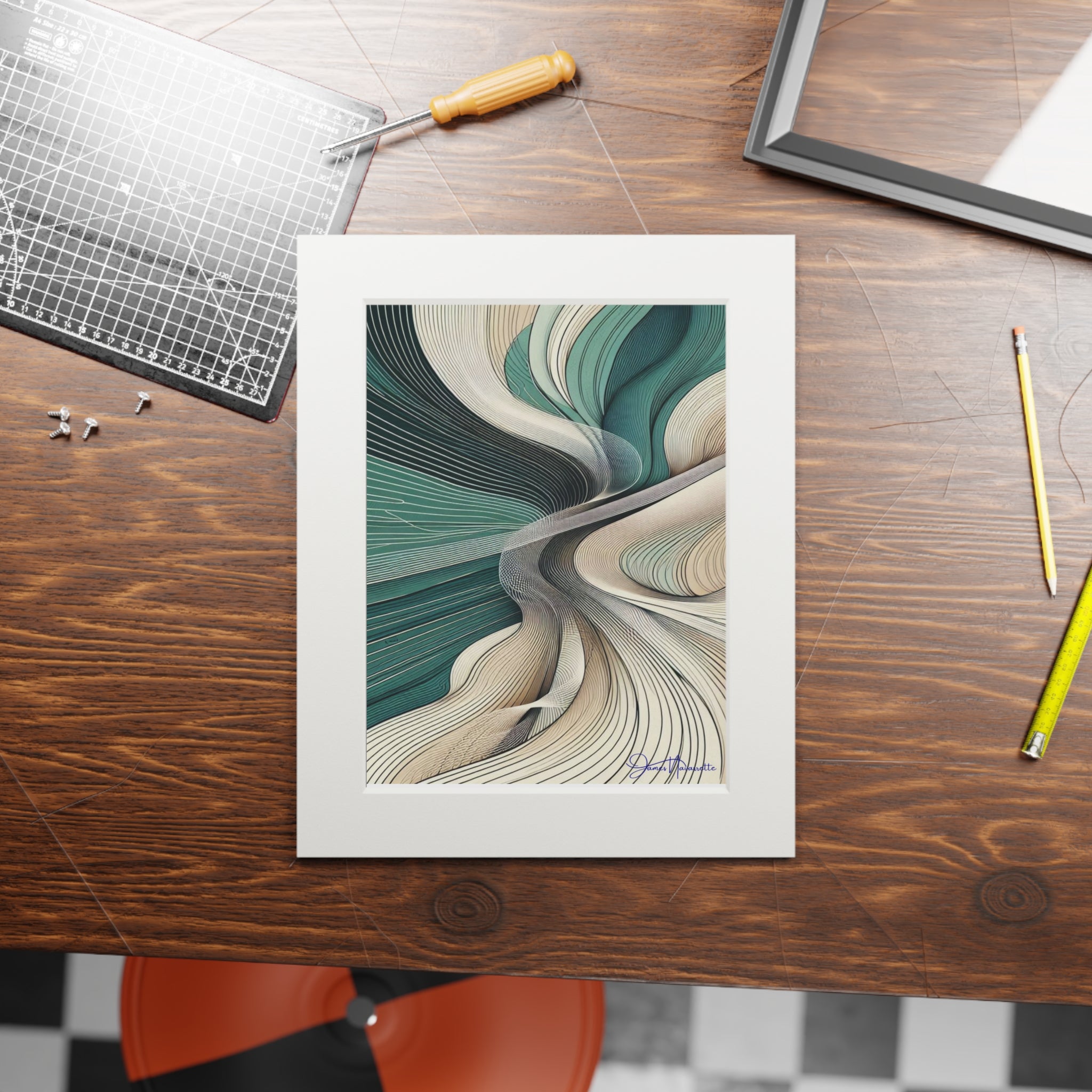 Framed abstract artwork on a wooden table with tools and a chair.