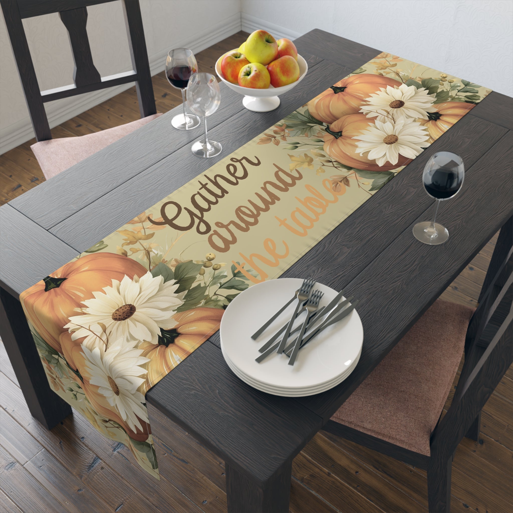 Table setting with a decorative table runner featuring pumpkins and flowers on a wooden table.