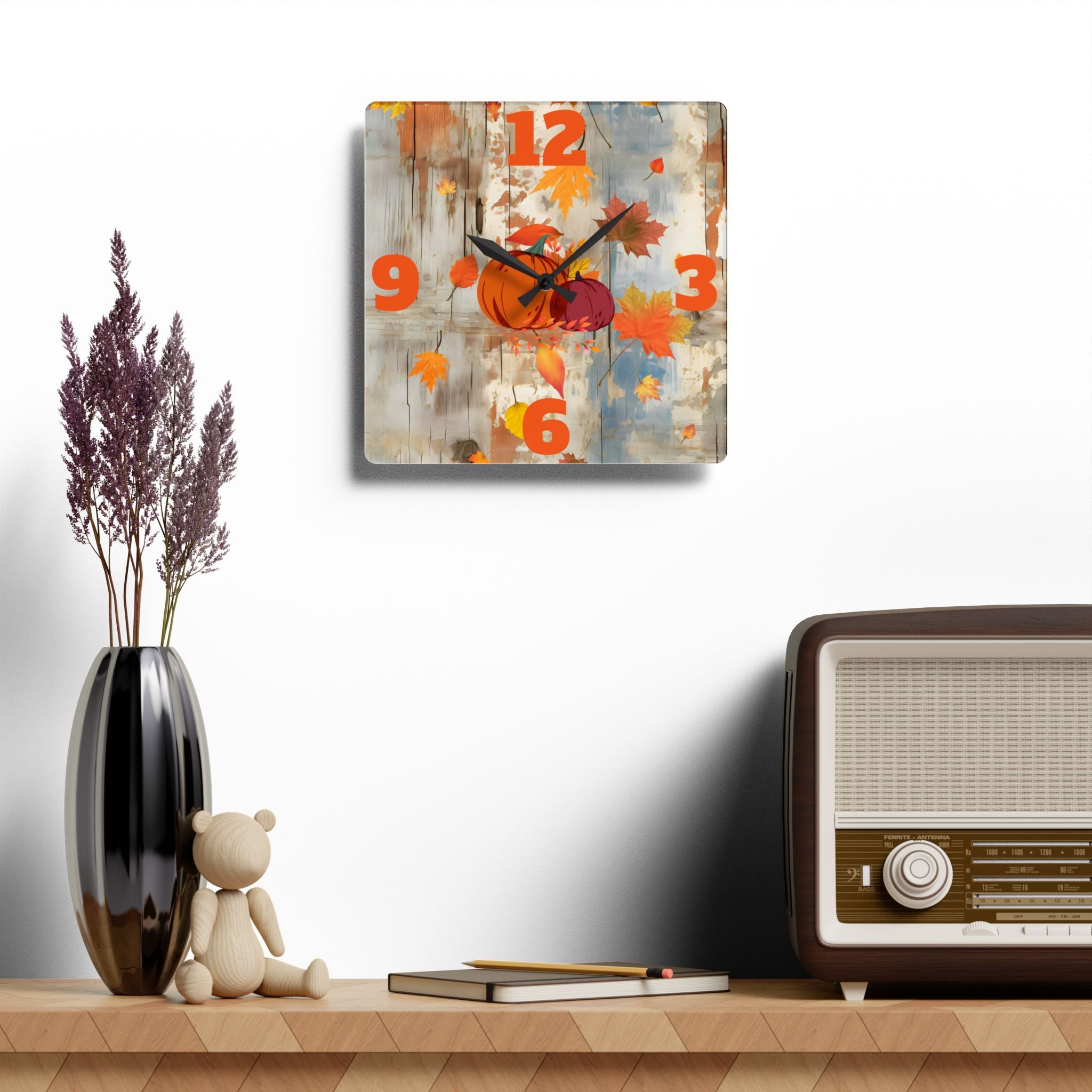 Decorative wall clock with autumn design on a shelf with a vase, teddy bear, and vintage radio.