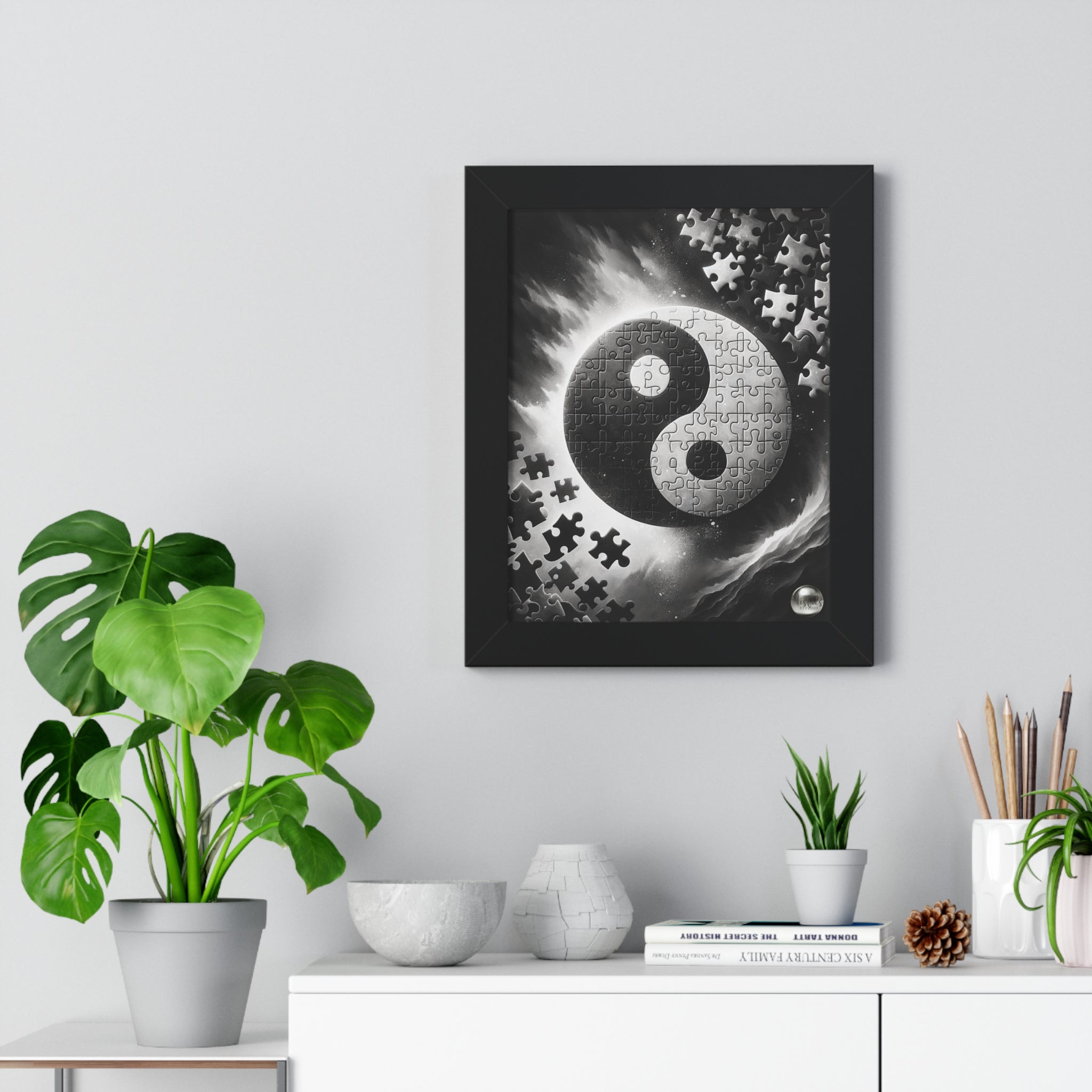 Framed artwork with a yin yang symbol and puzzle pieces on a wall with decorative items below.