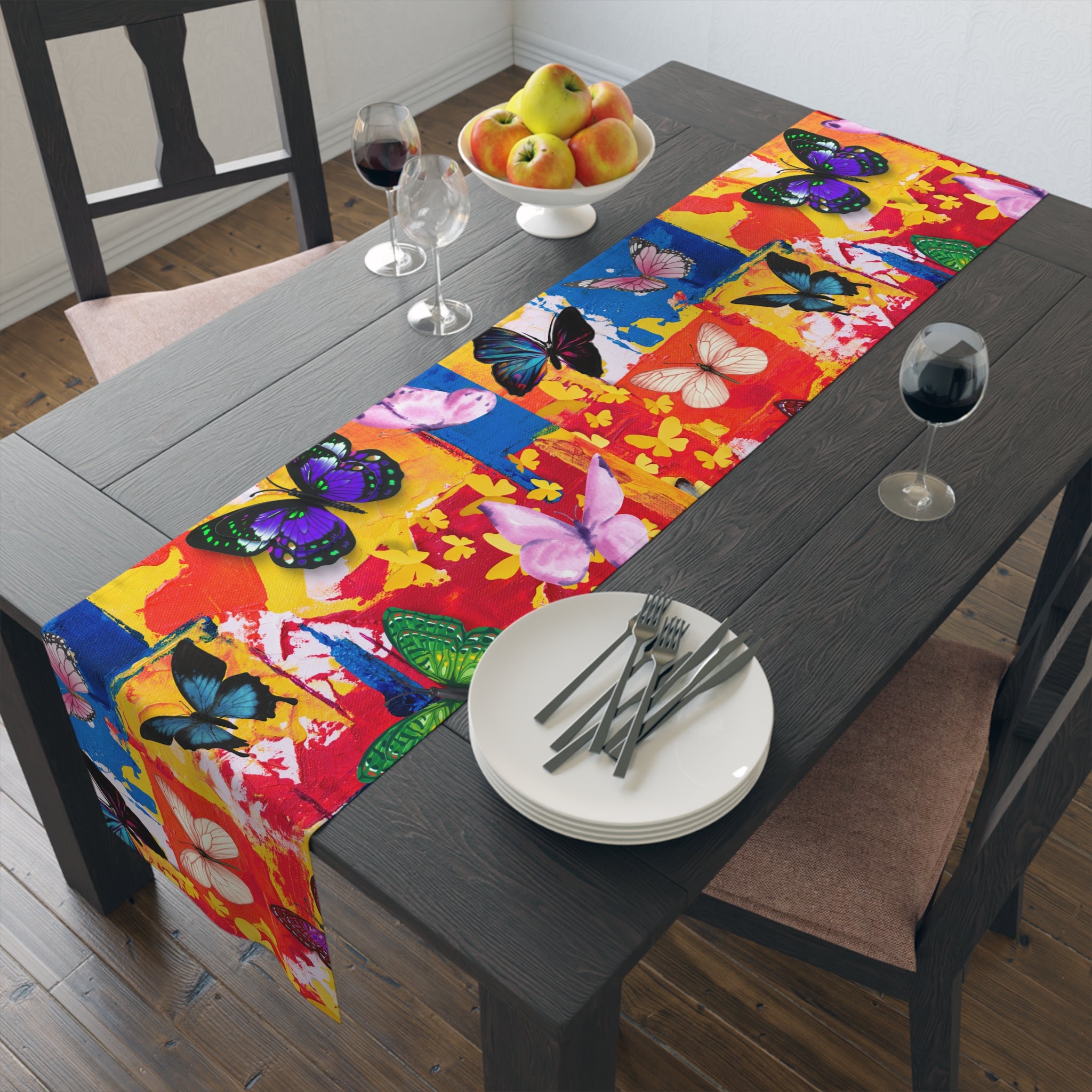 Colorful butterfly-patterned table runner on a dining table with fruit and wine glasses.