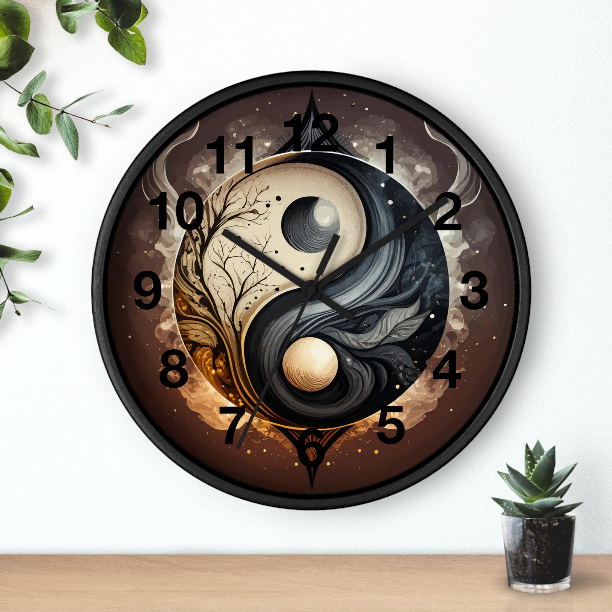 Decorative wall clock with yin yang design on a white wall with a plant and small pot.