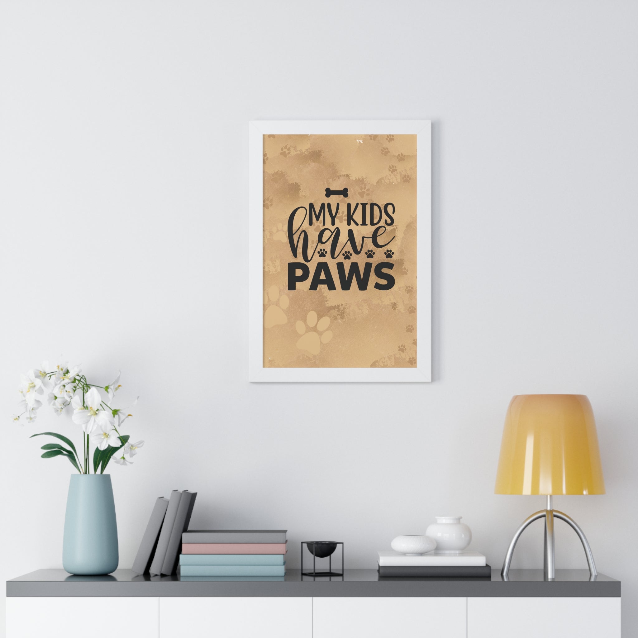 Framed print with 'My kids have paws' text on a wall above a desk with decor items.