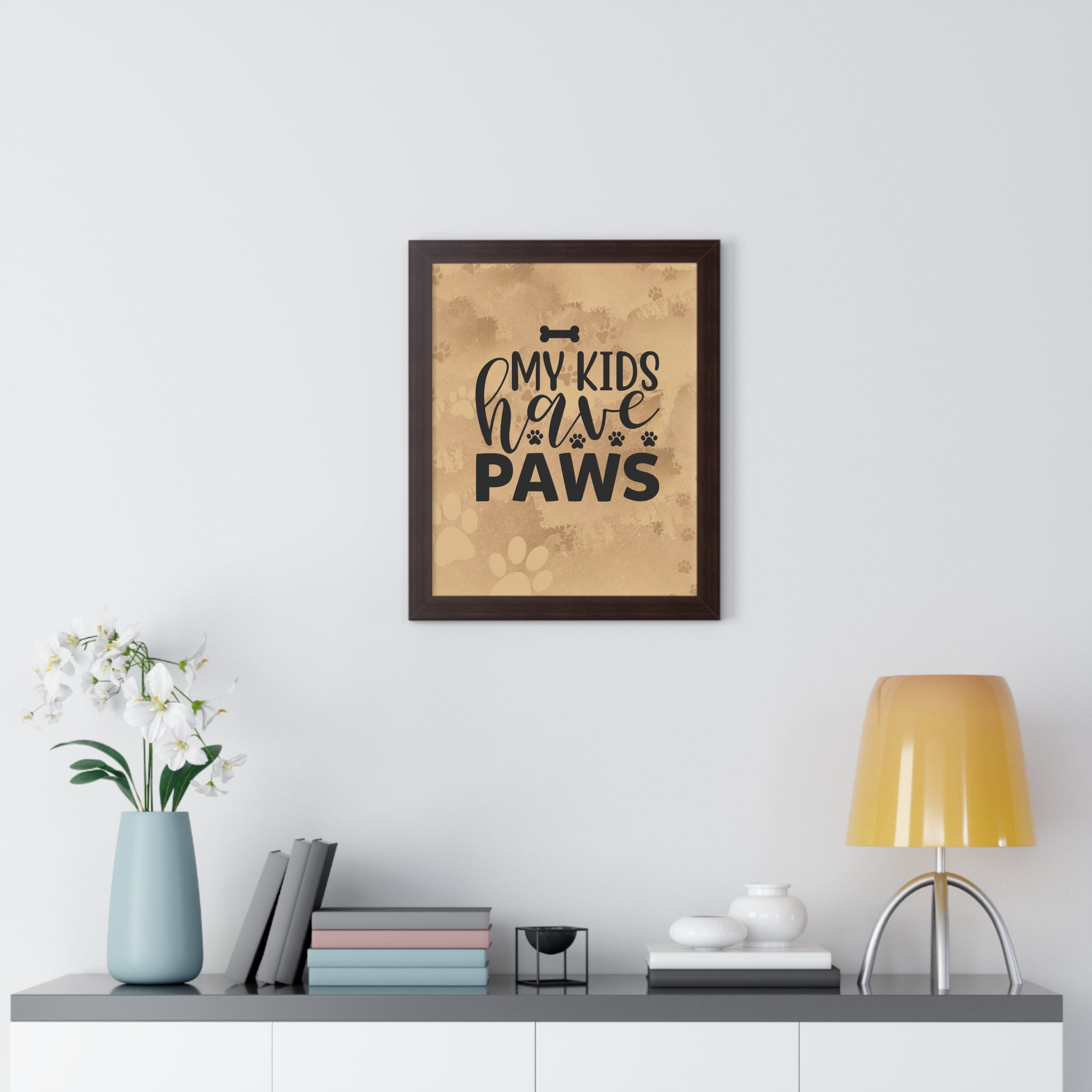 Framed print with 'My kids have paws' text on a wall above a desk with decor items.