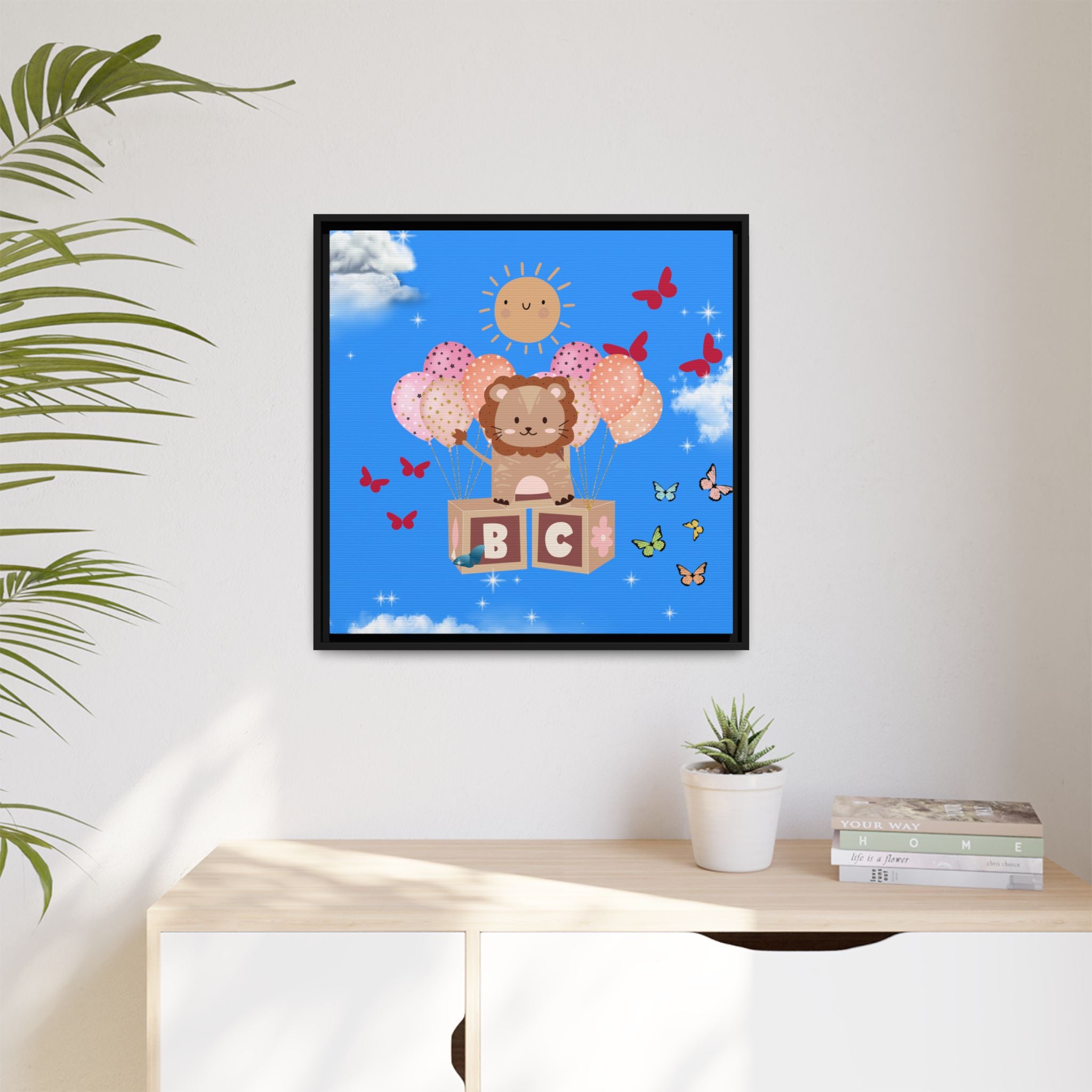 Framed artwork of a lion on blocks with balloons and butterflies, hanging above a desk.