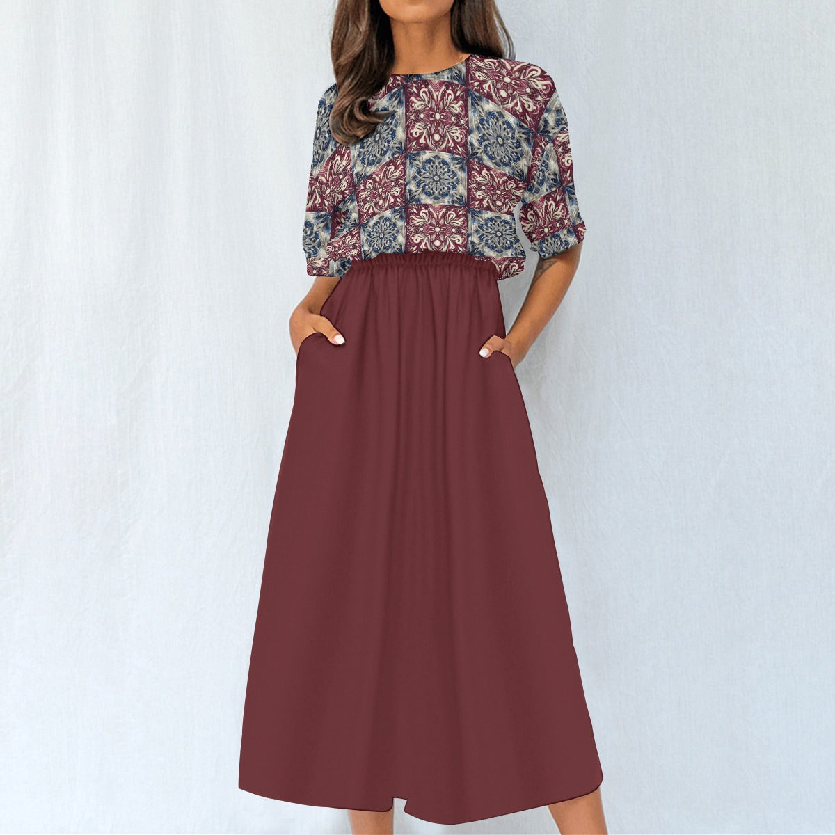 Woman wearing a patterned top and maroon skirt on a white background