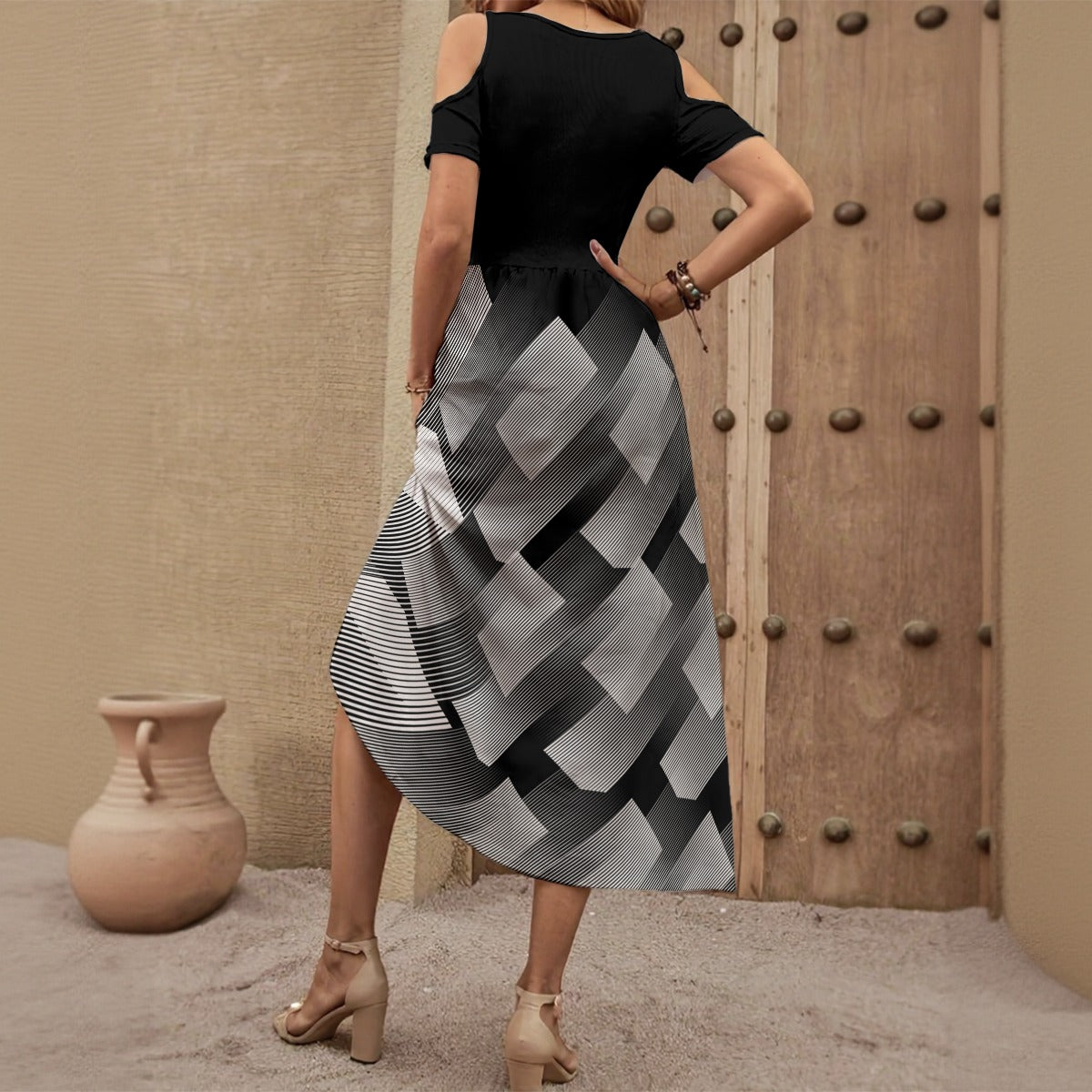 Woman wearing a black top and patterned skirt standing in front of a wooden door.