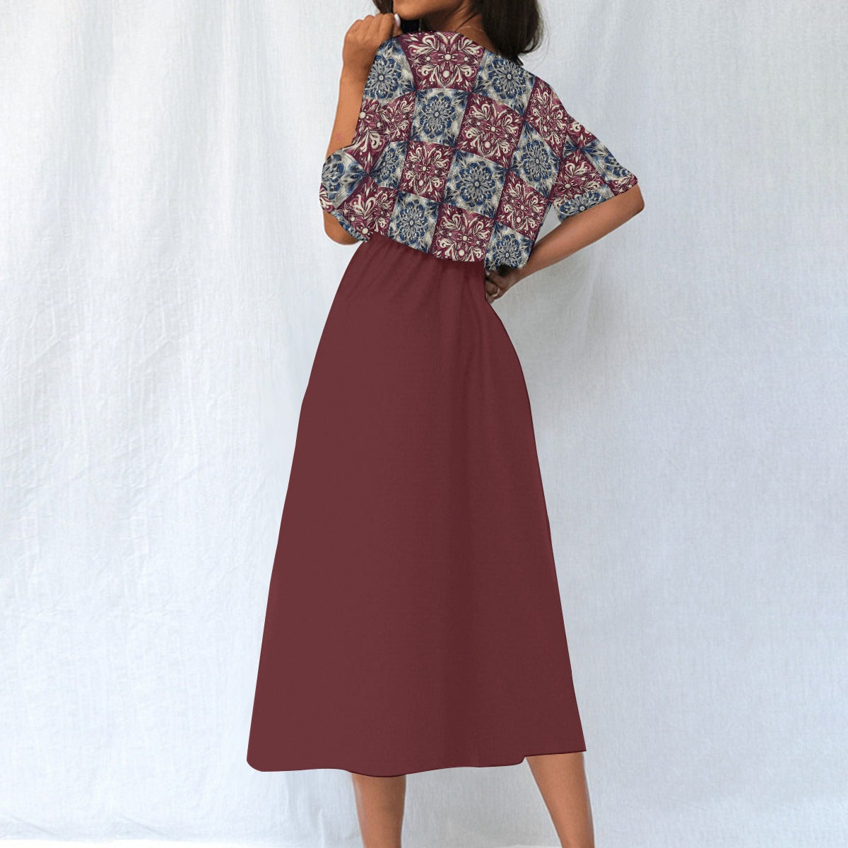 Woman wearing a patterned top and maroon skirt against a white background