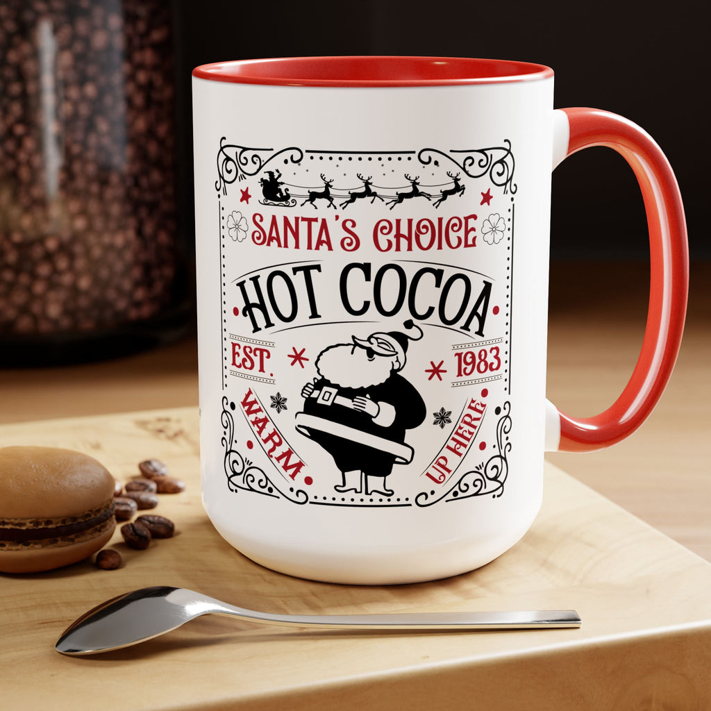 White mug with red interior and handle, featuring 'Santa's Choice Hot Cocoa' design, on a wooden surface with coffee beans and a spoon.