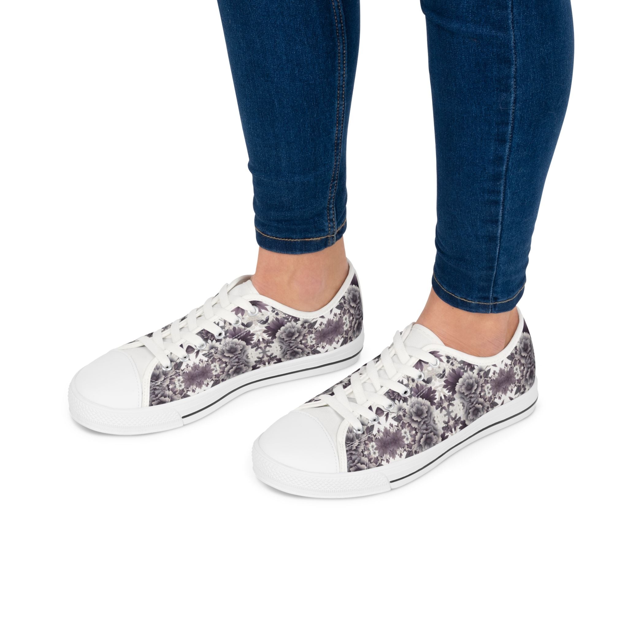 White sneakers with floral pattern worn with blue jeans on a white background